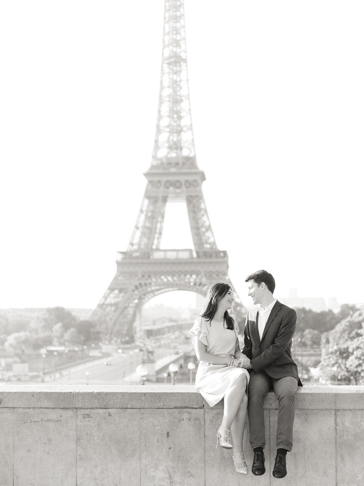 Un couple se regarde assis devant la tour eiffel. C'est un moment très romantique